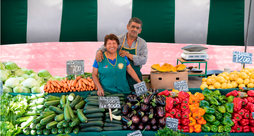 Pareja de feriantes con pecheras verdes en su puesto