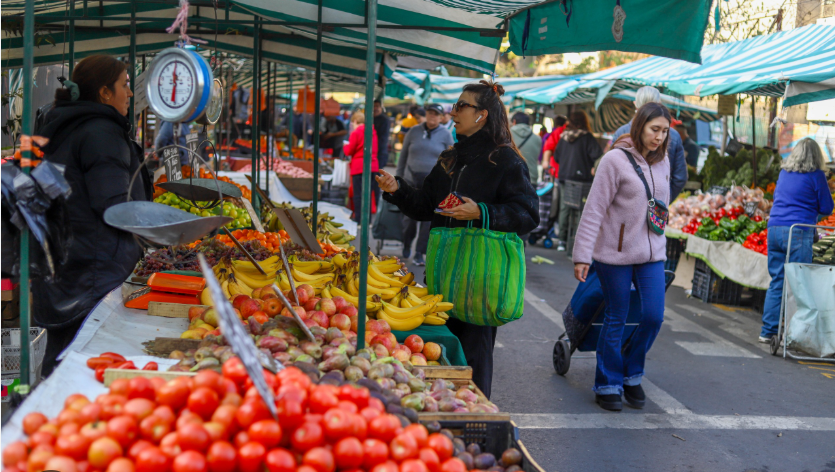 Pasillo de feria libre con toldos verdes y blancos y balanzas colgantes