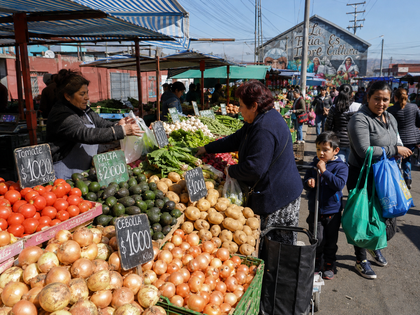 Puesto de feria libre chilena con cebollas y papas frente a un mural que dice La Feria Es Cultura